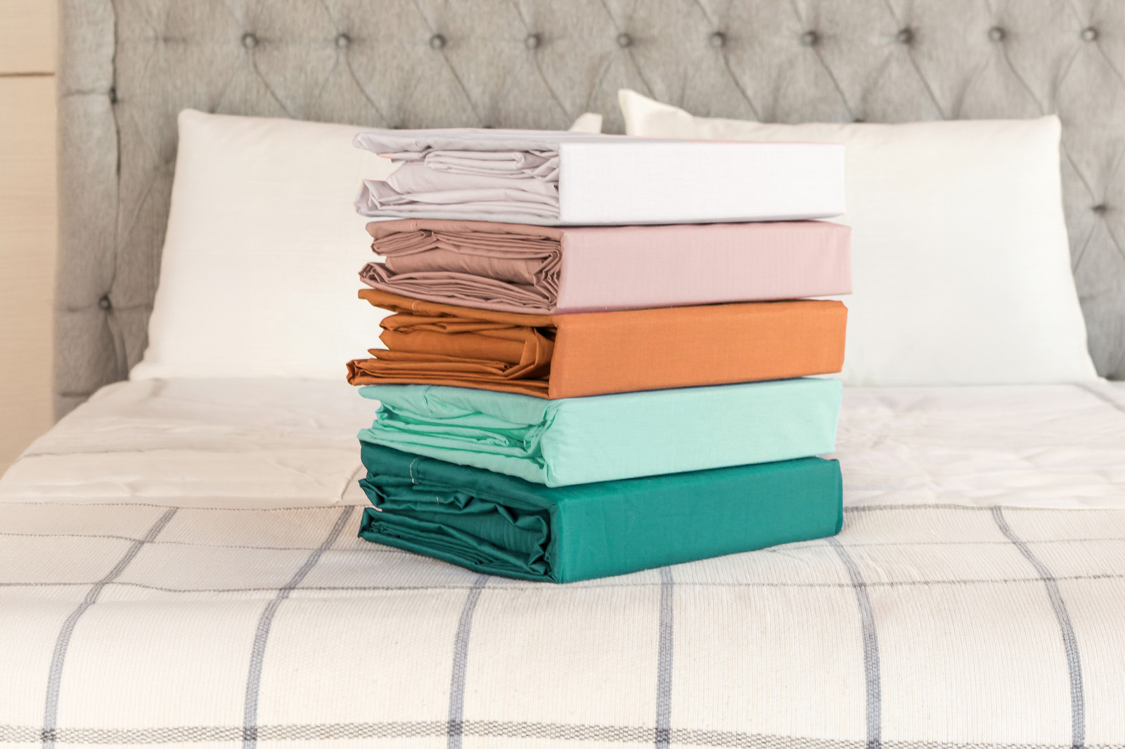 Picture of several bed sheet materials and colors on a bed