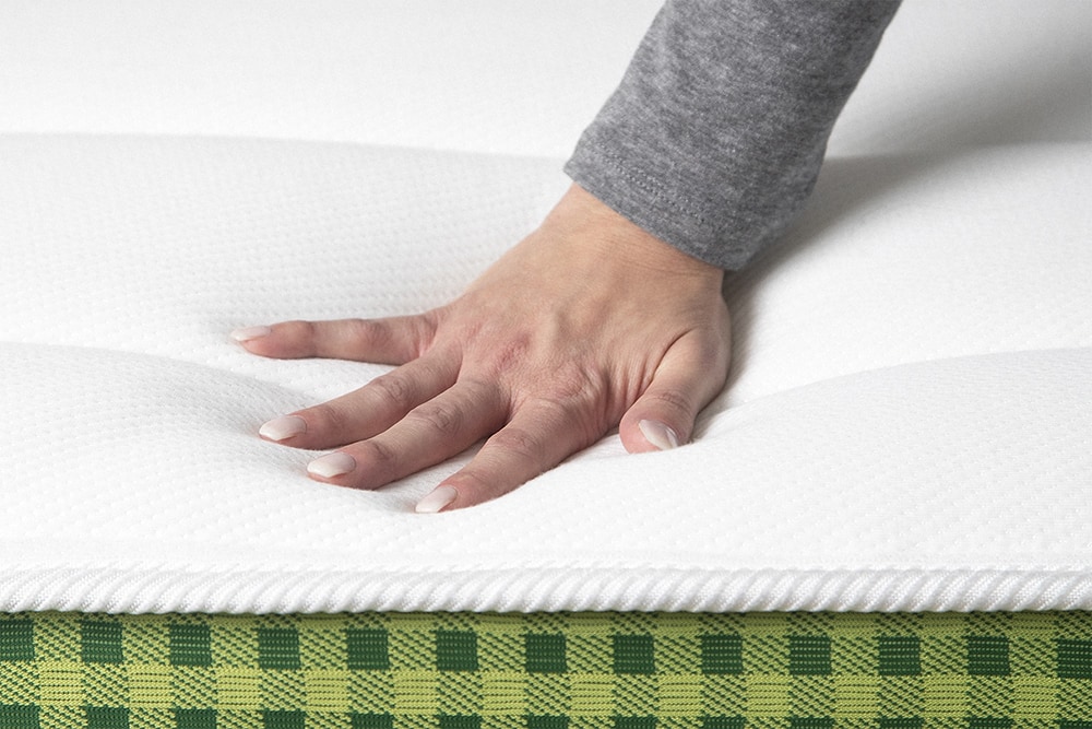A hand presses into the pillow quilted surface of the Brunswick mattress.