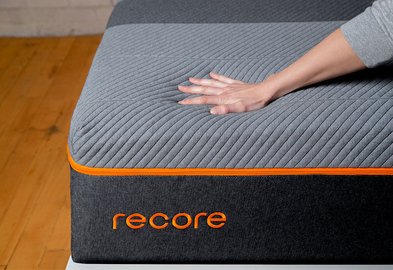 A hand pressed into the surface of the Recore mattress
