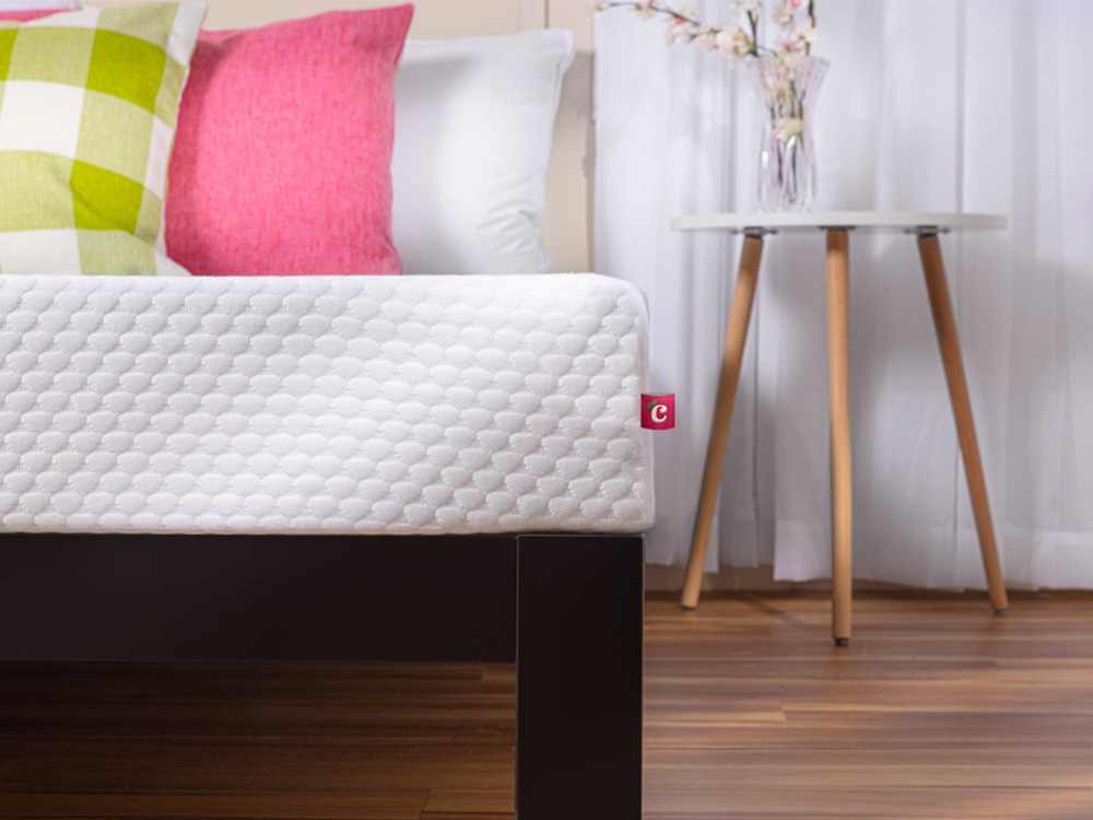 Front view of Cherry mattress on a bed in a bright, colourful bedroom