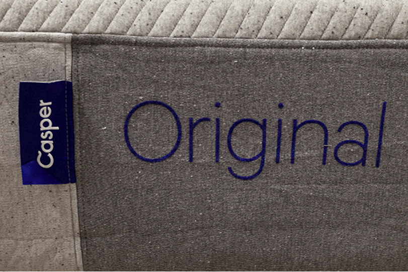 Image of the blue Casper mattress tag and 'Original' logo stitching on the grey Casper Original Mattress