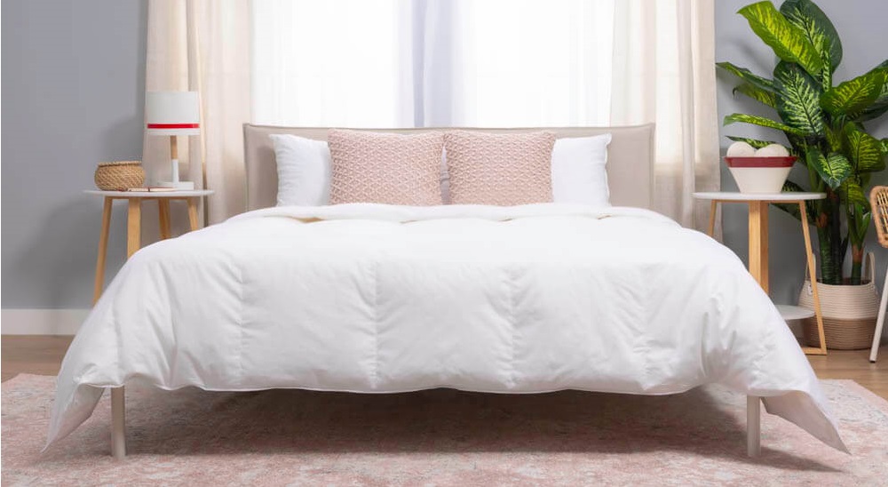 The white Douglas Canadian Down Duvet resting on a bed in a well-lit room with plants and modern decor.