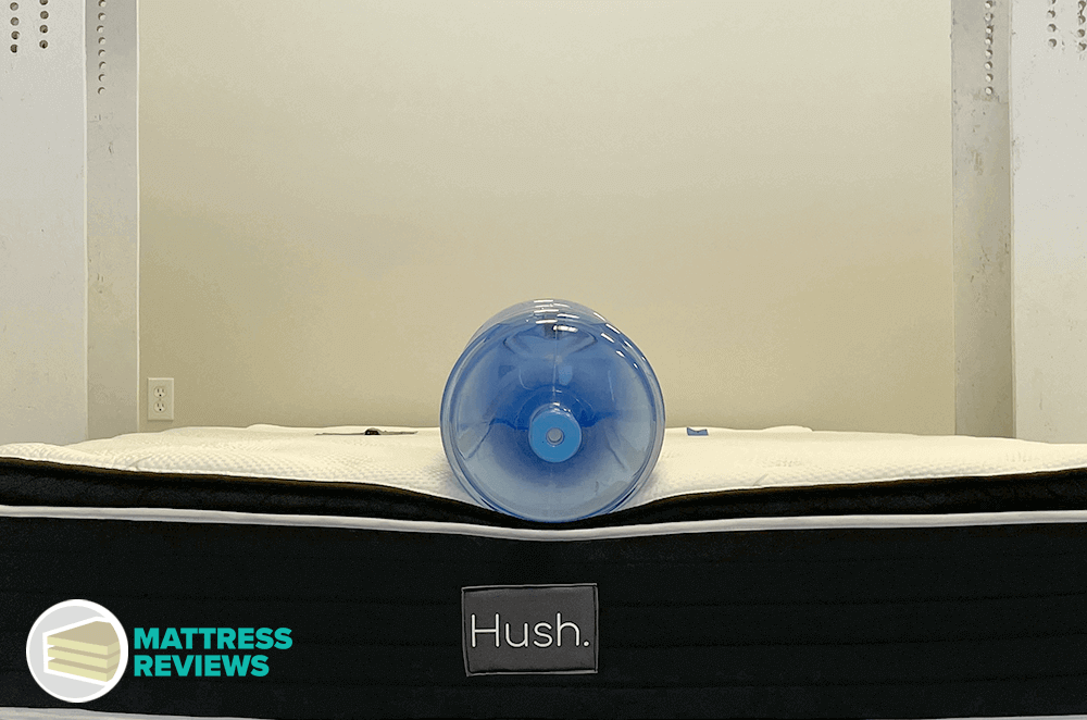 A heavy water jug sinks deep into the edge of a Hush pillow-top mattress to measure edge support