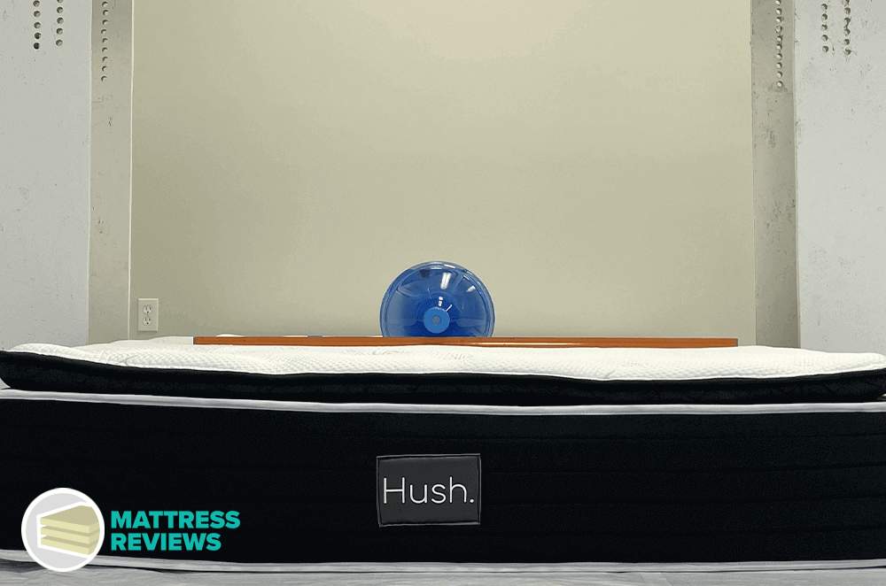 A heavy water bottle sinks into the top of a Hush pillow-top mattress to test firmness