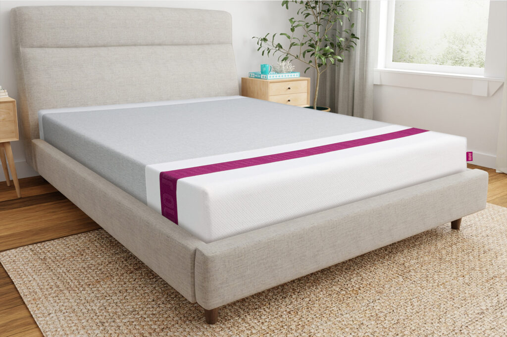 Front corner angle photo of a Juno mattress sitting on a bedframe in a bedroom