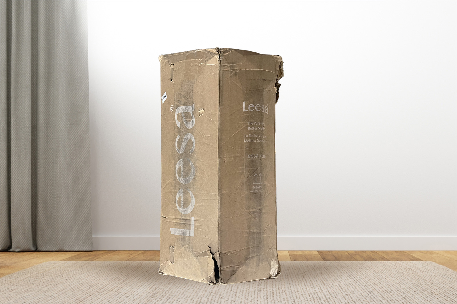 The leesa mattress box standing upright on a carpet in a bedroom