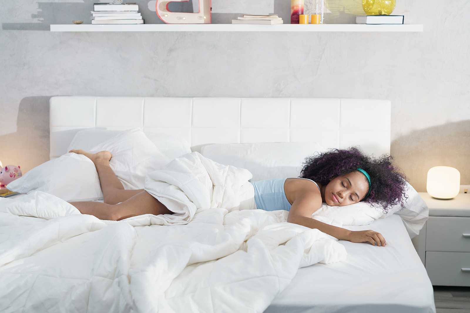 Image of a woman lying on a bed partially covered by a blanket