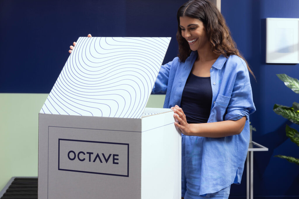 Women opening the Octave Mirage mattress box in her bedroom.